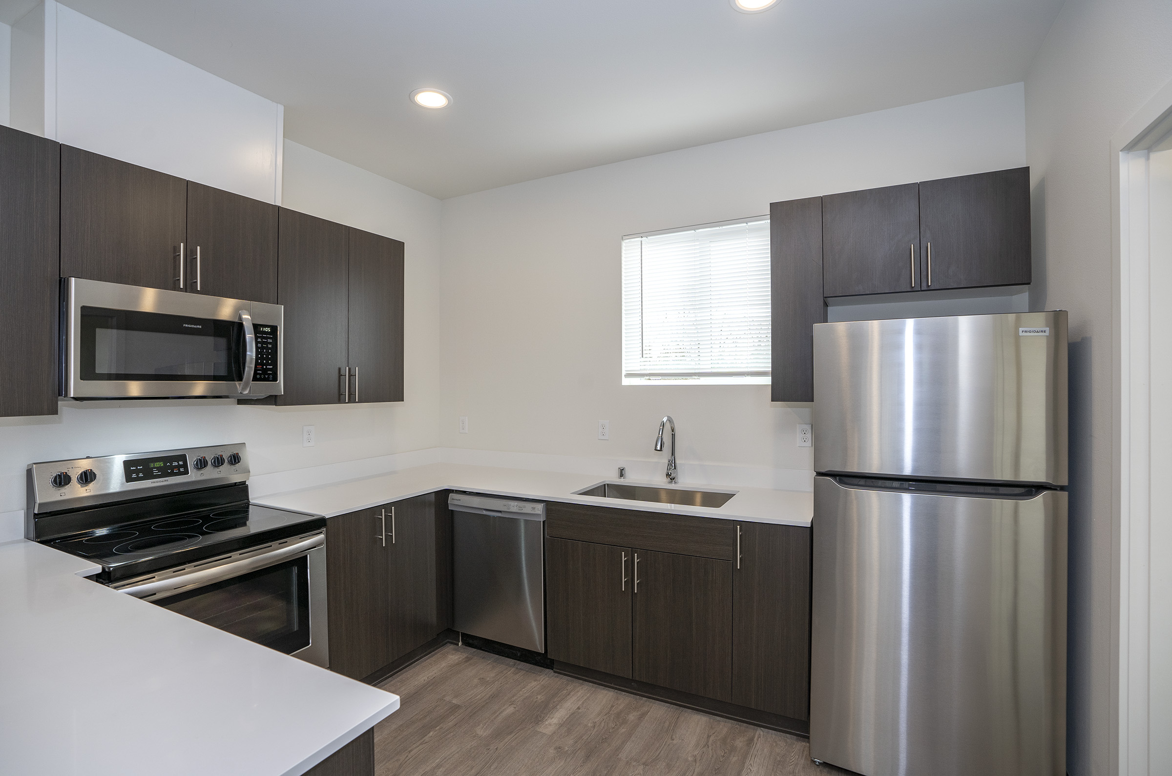 Modern kitchen with stainless steel appliances and quartz countertops — One-12 Townhomes Lakewood WA